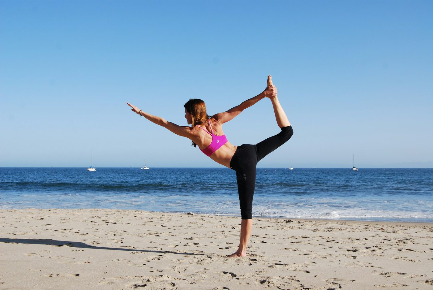 A woman stretching on a beach by the ocean